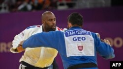 Teddy Riner, en blanc, face à Gela Zaalishvili de la Georgie dans la catégorie des +100kg à Doha, Qatar, le 13 janvier 2021. (Photo by - / AFP)