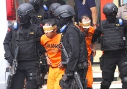 Petugas kepolisian Indonesia mengawal tersangka militan yang ditangkap dalam penggerebekan di Malang, Jawa Timur, Indonesia, 21 Februari 2016. (Foto: AP)