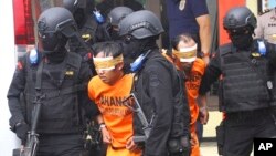Petugas polisi mengawal tersangka militan yang ditangkap dalam penggerebekan di Malang, Jawa Timur, 21 Februari 2016. (Foto: AP)