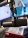 Studio Microphone in Radio Station with Female Host In Background