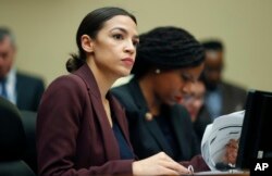 FILE - Rep. Alexandria Ocasio-Cortez, D-N.Y., left, looks over her notes during testimony by Michael Cohen, President Donald Trump's former lawyer, before the House Oversight and Reform Committee on Capitol Hill in Washington, Feb. 27, 2019.