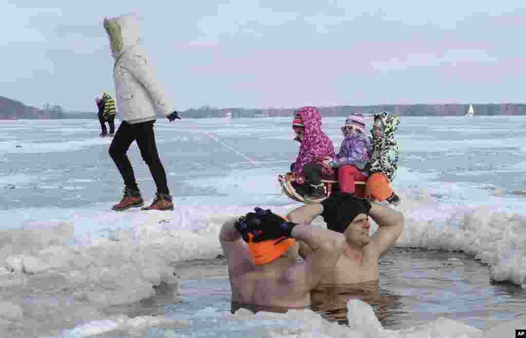 Children enjoy a sled ride past ice swimmers at the Zalew Zegrzynski lake in Nieporet, Poland.