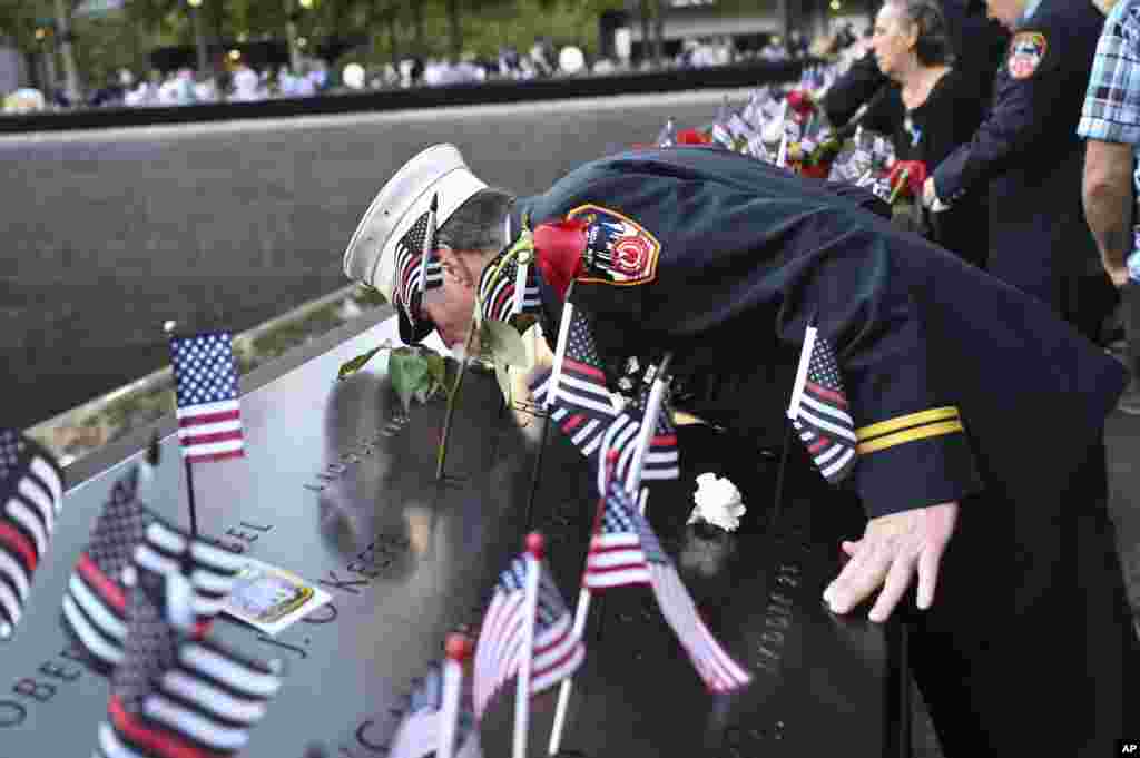 Retired Paramedic Chief Charlie Wells kisses the name of a relative killed in the attack on the World Trade Center at the National September 11 Memorial in New York on the 20th anniversary of the attacks, Sept. 11, 2021.