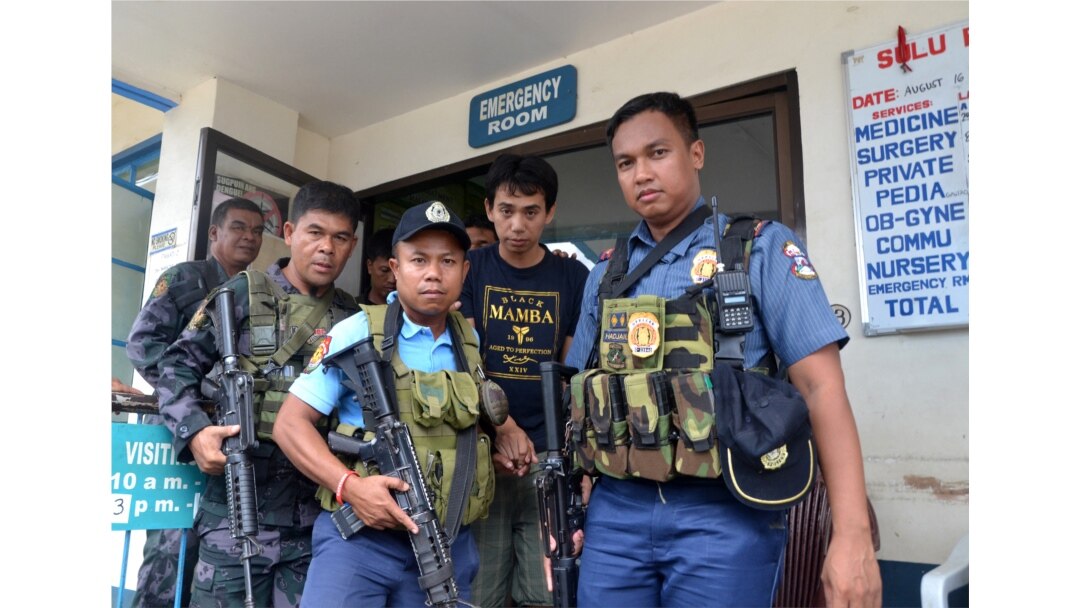 Polisi Filipina bersenjata mengawal warga negara Indonesia, Muhamad Sofyan ketika mereka meninggalkan rumah sakit di kota Jolo, Provinsi Sulu, di selatan pulau Mindanao pada 17 Agustus 2016, setelah dia melarikan diri dari para penculiknya, kelompok ekstr