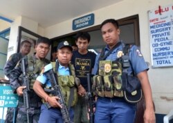 Polisi Filipina bersenjata mengawal warga negara Indonesia, Muhamad Sofyan ketika mereka meninggalkan rumah sakit di kota Jolo, Provinsi Sulu, di selatan pulau Mindanao pada 17 Agustus 2016, setelah dia melarikan diri dari para penculiknya, kelompok ekstr