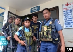 Polisi Filipina bersenjata mengawal warga negara Indonesia, Muhamad Sofyan ketika mereka meninggalkan rumah sakit di kota Jolo, Provinsi Sulu, di selatan pulau Mindanao pada 17 Agustus 2016, setelah dia melarikan diri dari para penculiknya, kelompok ekstr