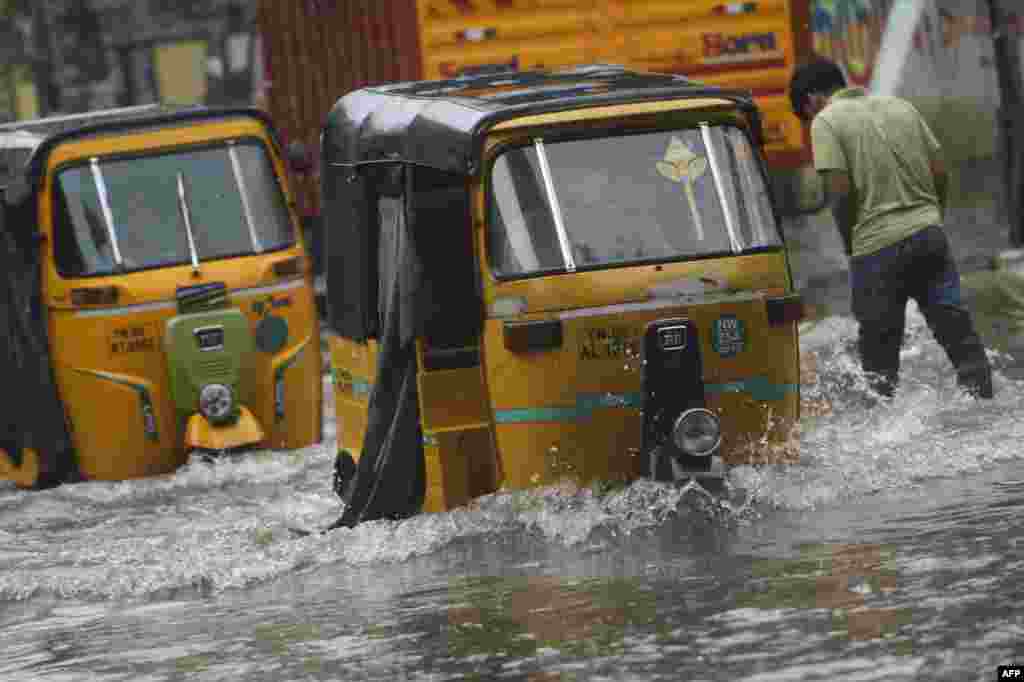 Auto-rickshaws make their way along a waterlogged street after a heavy rainfall in Chennai, India.