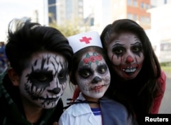 Orang-orang yang mengenakan kostum berpose untuk foto selama perayaan Halloween di La Paz, Bolivia, 31 Oktober 2018. (Foto: Reuters / David Mercado)