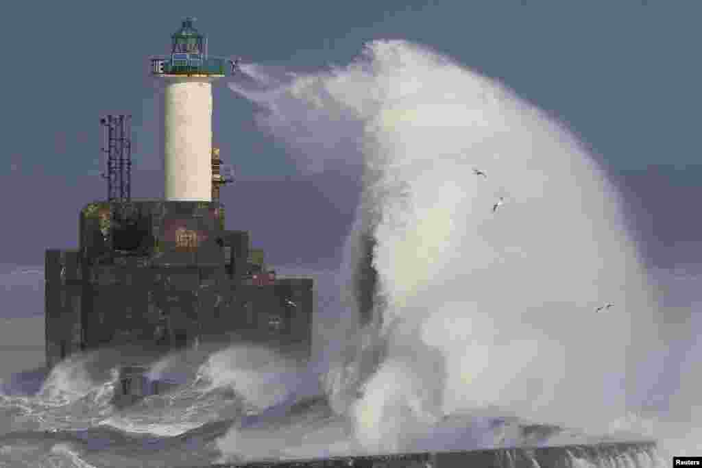 Waves crash against a lighthouse as the wind blows at around 100 kph (62 mph), in Boulogne-sur-Mer, northern France.