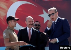 Turkish President Tayyip Erdogan, accompanied by Interior Minister Suleyman Soylu, blows a watchmen whistle during a ceremony in Istanbul, Aug. 25, 2017.