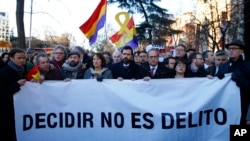 Presiden Parlemen Catalonia, Roger Torrent (tengah) dan Presiden regional Catalan Quim Torra (kanan tengah), memegang spanduk bertuliskan dalam bahasa Spanyol: "Memilih Bukan Kriminal", di luar Mahkamah Agung Spanyol di Madrid, Selasa, Februari 12, 2019.