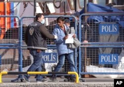 Ảnh tư liệu - Cảnh sát Thổ Nhĩ Kỳ hộ tống một di dân sau khi chuyến tàu đầu tiên đưa những người di cư từ đảo Lesbos, Ai Cập, cập bến ở cảng Dikili, Thổ Nhĩ Kỳ, đưa vào thực hiện một kế hoạch của EU nhằm ngăn chặn người di cư vào châu Âu, ngày 4 tháng 4 năm 2016.