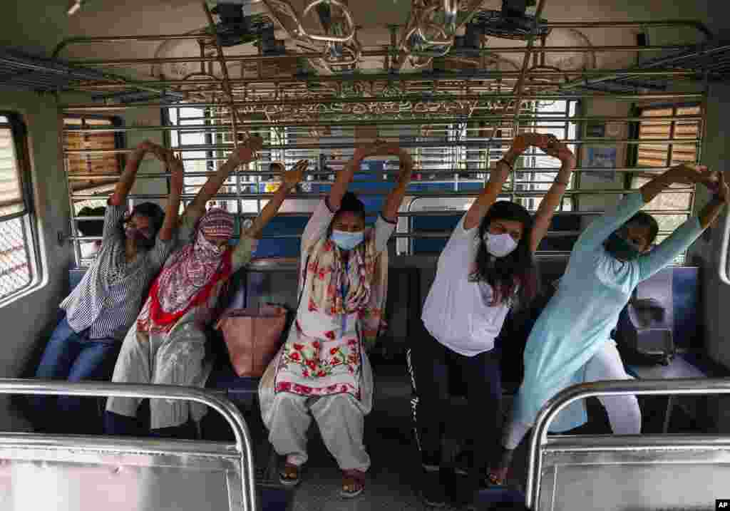 Commuters in a suburban train take part in a yoga session to mark International Yoga Day in Mumbai, India.