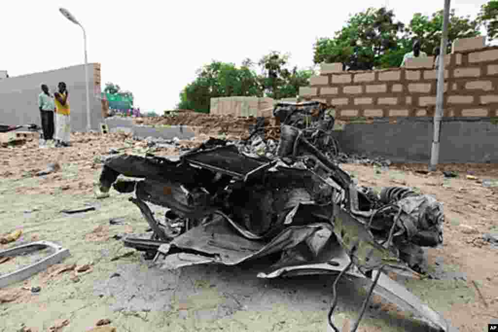 A damaged car is seen along a road after a bomb blast in Maiduguri in the northeastern state of Borno, June 29, 2011