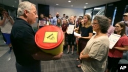 David Gray, left, director of external affairs at the Environmental Protection Agency Region VI office, accepts a barrel of letter from members of the Texas Campaign for the Environment at the EPA office in Dallas, Oct. 12, 2017. The letters to the EPA are calling for saving federal cleanup programs under the Trump Administration. The EPA has approved a plan to remove sediments laced with highly toxic dioxin from a partially submerged Superfund site near Houston damaged during Hurricane Harvey. 