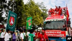 Supporters of Myanmar's opposition leader Aung San Suu Kyi's National League for Democracy party, on the party's campaign truck, right, pass an office of the rival Union Solidarity and Development Party in Meiktila, Mandalay Region, Myanmar, Nov. 4.