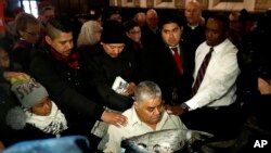 Catalino Guerrero, bottom center, is surrounded by family and supporters as they pray at Grace Episcopal Church during a gathering after his immigration hearing, March 10, 2017, in Newark, N.J. Guerrero, who arrived in the U.S. illegally in 1991, was granted a 60-day extension to seek a stay of deportation.