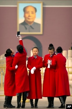 Hospitality staff members pose for a selfie near the portrait of Chinese leader Mao Zedong during the opening session of the Chinese People's Political Consultative Conference (CPPCC) held in Beijing's Great Hall of the People, Saturday, March 3, 2018. (A