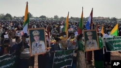 In this image provided by the Military True News Information Team, supporters of the military government hold nationalistic banners and portraits of Senior General Min Aung Hlaing during a rally on Feb. 1, 2022 in Naypyitaw, Myanmar. 