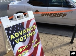 A sign displays absentee voting hours in Marietta, Ga., as a Cobb County sheriff's deputy sits in his vehicle, Oct. 17, 2016. Facing unprecedented warnings of a "rigged" election from Donald Trump, state officials around the country are rushing to reassure the public.r