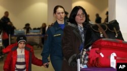 A Russian woman and her daughter, left, are escorted by a Russian emergency situation officer leave passport control zone just after arrivingl from Beirut in Moscow Domodedovo airport, January 23, 2013.