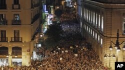 Demonstrators raise their arms just after midnight as they fill up Madrid's Puerta del Sol, spilling into sidestreets, early May 21, 2011