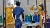 FILE - A Doctors Without Borders health worker takes off his protective gear under the surveillance of a colleague at a treatment facility for Ebola victims in Monrovia, Sept. 29, 2014. 