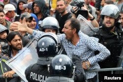 A migrant man reacts as he is surrounded by Slovenian police at the Slovenia-Croatia border crossing in Rigonce, Slovenia, Sept. 19, 2015.