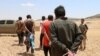 FILE - Men, who the Democratic Forces of Syria fighters claimed were Islamic State fighters, walk as they are taken prisoners after SDF advanced in the southern rural area of Manbij, in Aleppo Governorate, Syria, May 31, 2016. 