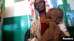 A Somali woman holds a malnourished child as they wait for medical attention at Banadir hospital in Mogadishu, April 28, 2014.