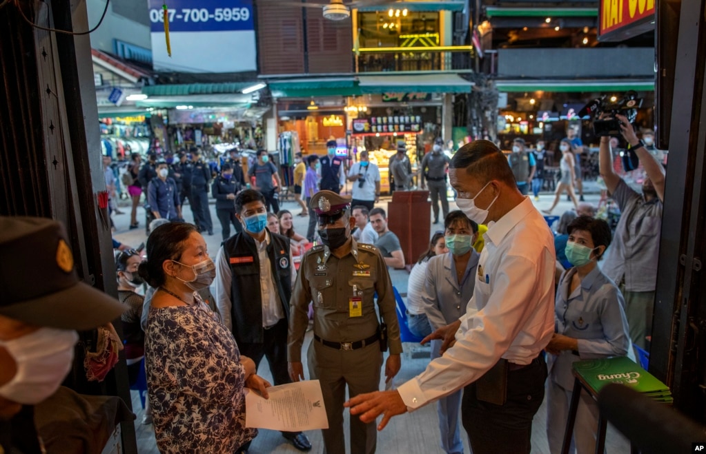 Los funcionarios tailandeses notifican al dueño de un bar del cese de sus operaciones en Khao San Road, un lugar popular entre los turistas extranjeros en Bangkok, Tailandia.