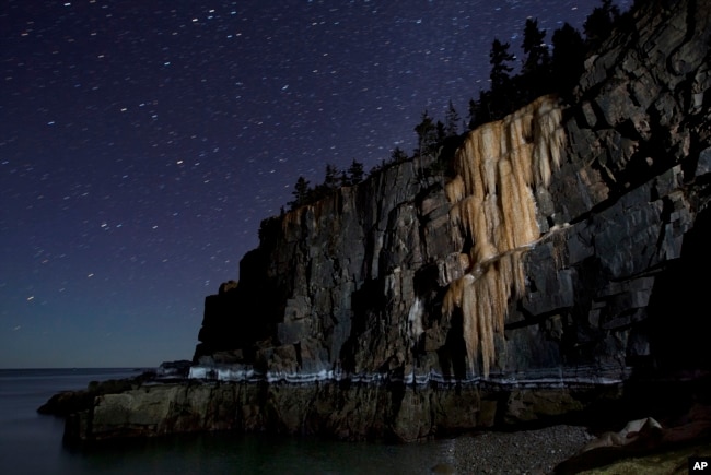 Like a frozen waterfall, a wall of ice more than 40-feet-high stretches down to the high-tide line on Otter Cliffs overlooking the Atlantic Ocean, in this time-exposure made Thursday, March 6, 2014, at Acadia National Park in Maine.