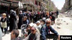 FILE - Residents wait to receive food aid distributed by the U.N. refugee agency at the Palestinian refugee camp of Yarmouk, south of Damascus, Syria, May 2014.