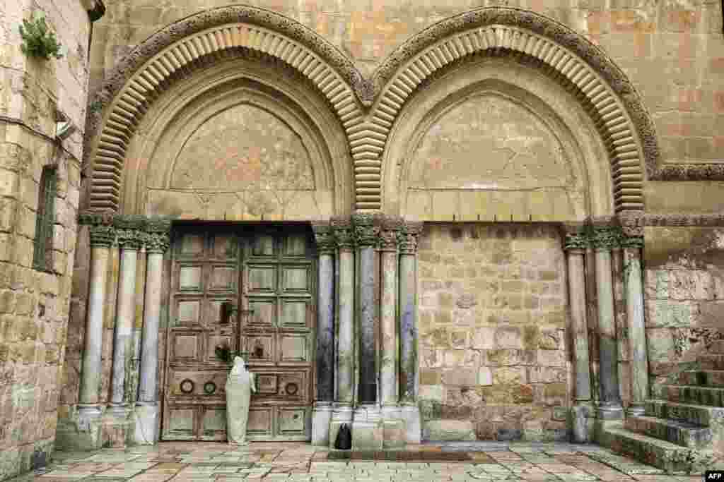 A Christian pilgrim stands in front of the closed door of the Holy Sepulchre Church in Jerusalem&#39;s Old City on Good Friday, amid the COVID-19 pandemic crisis, when all cultural sites in the Holy Land are shuttered.