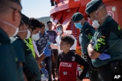 Guardia Civil officers joke with a young migrant disembarking at the port of Barbate, southern Spain, after being rescued by Spain's Maritime Rescue Service in the Strait of Gibraltar, June 27, 2018.