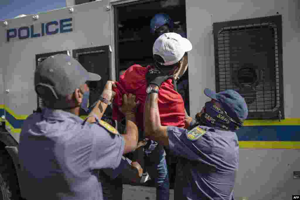 South African Police Service (SAPS) officers force a student member of the Economic Freedom Fighters (EFF) inside a police vehicle during a protest in Braamfontein, Johannesburg.