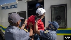 Des agents du Service de police sud-africain embarquent un étudiant membre des combattants de la liberté économique (EFF) à l'intérieur d'un fourgon de police lors d'une manifestation à Braamfontein, Johannesburg, le 10 mars 2021.