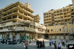 People wait for a bus in Aleppo, Syria, Sept. 12, 2017.