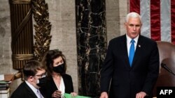 US Vice President Mike Pence (C) arrives to preside over a joint session of Congress counting the electoral votes for President after they resumed the session following protests at the US Capitol in Washington, DC, January 7, 2021. - US lawmakers formally
