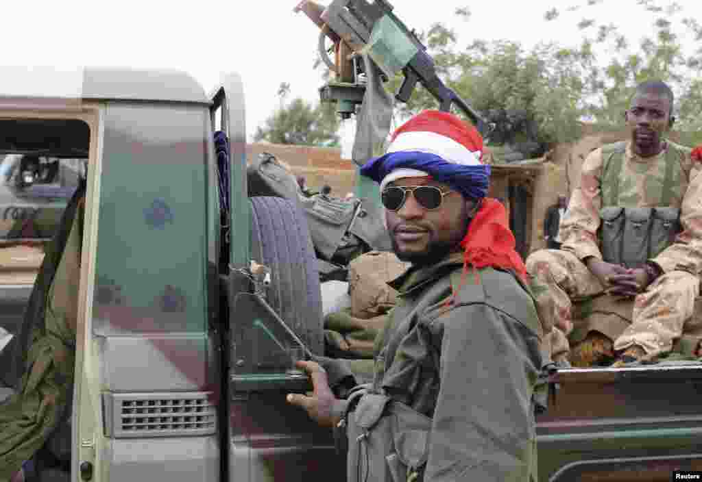 Un soldat malien arborant un drapeau français se tient près d'un véhicule récemment capturé à Gao.