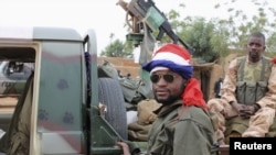 Binh sĩ Mali với cờ Pháp quấn quanh đầu đứng cạnh một chiếc xe quân sự tại thị trấn Gao.