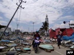 Warga melintas jalan yang penuh dengan puing-puing setelah gempa dan tsunami melanda Palu, Sulawesi Tengah, 29 September 2018.