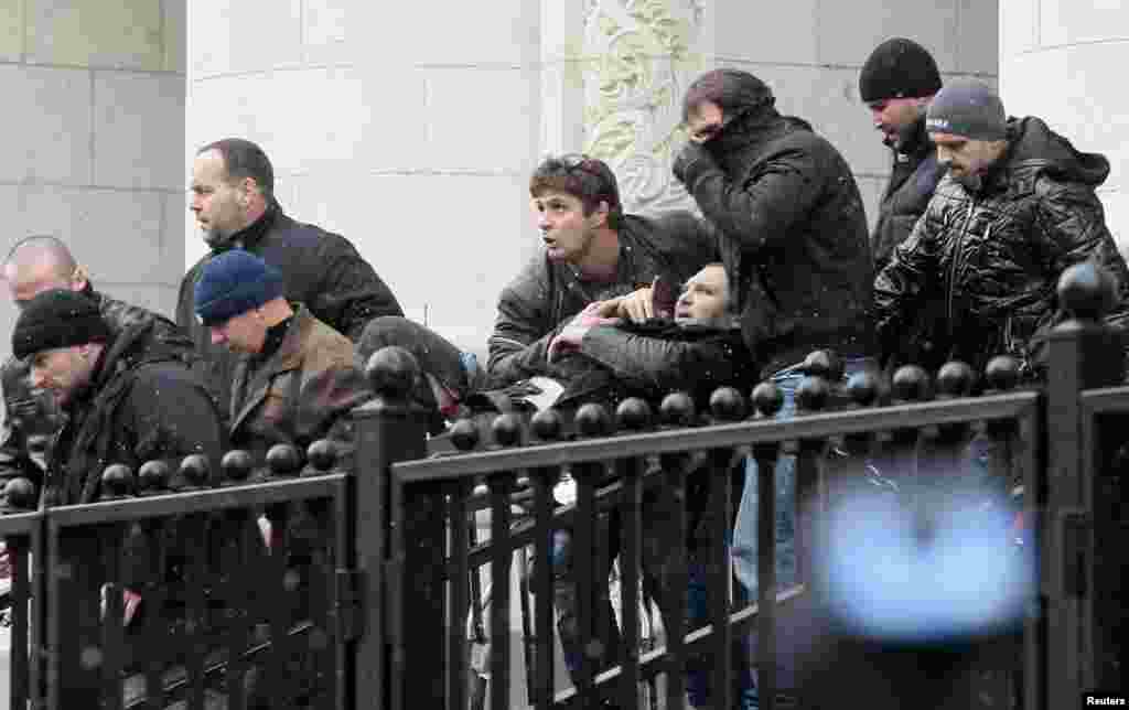 Bodyguards carry Zlatomir Ivanov, center, after he was shot in front of the central court building in downtown Sofia. An unidentified gunman shot and wounded the reputed Bulgarian crime boss, nicknamed 'The Beret', the latest blow to the cener-right government's efforts to to restore the rule of law and improve the Balkan country's image.