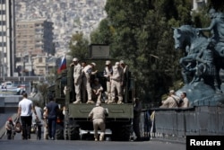 FILE - Russian soldiers stand on a truck in central Damascus, Syria, Sept. 14, 2018.