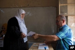 A woman receive a voting bill at a polling station as Kurds vote for independence in the disputed city of Kirkuk, Sept. 25, 2017. Iraq's Kurdish region vote in a referendum on whether to secede from Iraq.