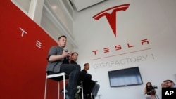 FILE - Elon Musk, CEO of Tesla Motors Inc., left, discusses the company's new Gigafactory in Sparks, Nevada, July 26, 2016. Tesla announced in September that it had been selected to build a battery storage project at the Mira Loma electricity substation i
