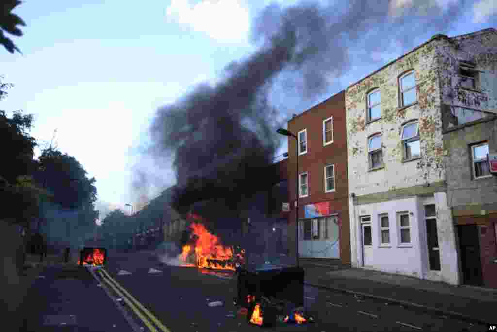 Burning garbage bins are set on fire by rioters in Hackney, east London, Monday Aug. 8, 2011. Youths set fire to shops and vehicles in a host of areas of London _ which will host next summer's Olympic Games _ and clashed with police in the nation's centra