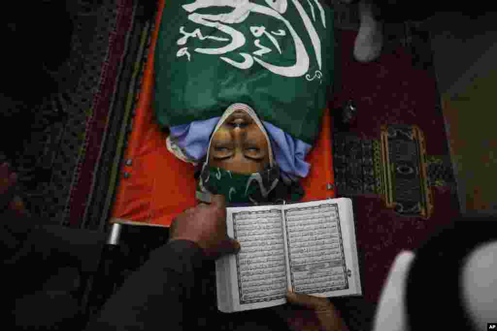 A Palestinian reads from the Quran during the funeral of Munir Badarin, who was shot during clashes with Israeli soldiers in the West Bank village of Samoa, south of Hebron, July 14, 2014.