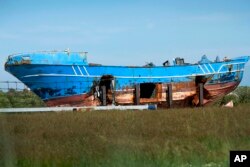 FILE - The wrecked fishing boat that capsized and sunk on April 18, 2015, off the coast of Libya, lies outside a NATO base in the Sicilian town of Mellili, Italy, Oct. 8, 2016.