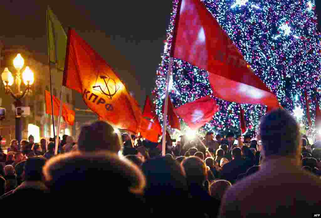 Những người ủng hộ Đảng Cộng sản Nga cầm cờ với màu sắc và biểu tượng của đảng này trong một cuộc biểu tình chống kết quả bầu cử. (AP/Alexander Zemlianichenko)